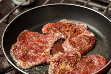 Beefsteaks are fried in a pan. Frying fresh beef. Hot meat in a frying pan.
