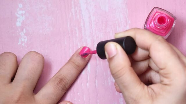 women applying nail polish on finger top down .
