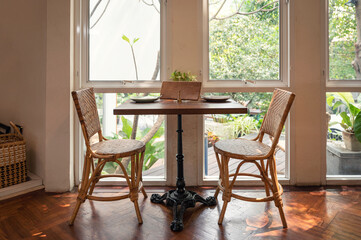 Wooden dining table with rattan chair and cutlery at beside window