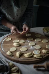 Foto op Canvas Step by step process of making Ukrainian pyrogy (Polish pierogi) with cottage cheese. Woman making pyrogy sitting by the table. © Sofiia.Popovych