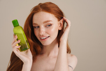 Photo of happy redhead shirtless girl posing with shampoo