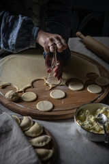 Step by step process of making Ukrainian pyrogy (Polish pierogi) with cottage cheese. Cutting dough rounds with glass.