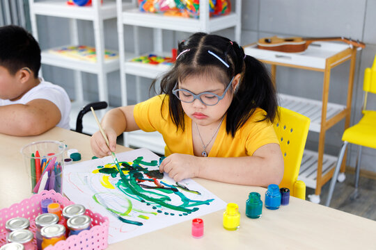 Asian girl with Down's syndrome painting in art class.