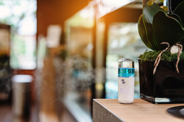 Alcohol nano mist sprayer for hand cleaning to prevent the spread of the Corona virus (Covid-19) to serve customers at coffee shop. Modern health technology. New normal lifestyle. Selective focus