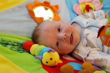 smiling happy cute baby child infant playing with toys on the play carpet