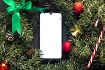 Smartphone with screen on lies in the middle of Christmas decorations.