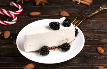 Pieces of delicious cheesecake with blackberries on dark wooden background