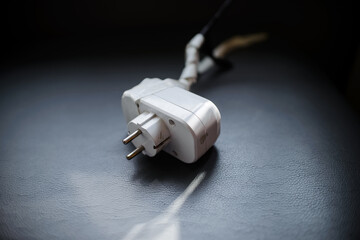Electrical plug in a damaged cable, close-up on a blue background. Broken socket