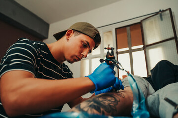 Young tattoo artist working in his professional studio.