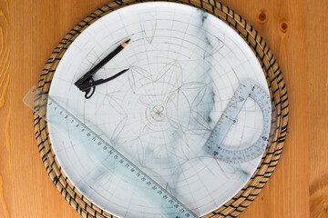 Pencil markup on decorative plate or platter, protractor, ruler, compass