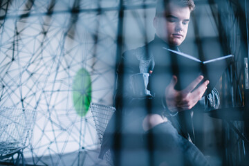 Serious young male reading book in cafe