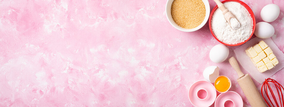 Baking background. Ingredients for baking - flour, eggs, butter, sugar on pink background flat lay. Baking or cooking cakes or donuts. Top view, long format with copy space