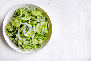Homemade sauerkraut salad of sliced cucumbers in a bowl on a gray background. Fermented vegetables. Vegetarian vegan food. Healthy food, seasonal preservation of vegetables. Top view. Copy space.