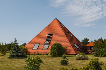 Fototapeta na wymiar House build as pyramid. Tiled roof. Oriental approach used in Europe.