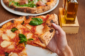 woman Hand takes a slice of Pizza Margherita or Margarita with Mozzarella cheese, tomato, olive. Italian pizza on wooden table background
