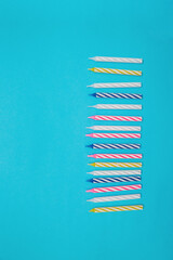 Colorful candles are placed in a row for a birthday cake on a blue background.