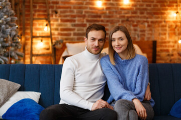 Obraz na płótnie Canvas Portrait of beautiful smiling couple hugging at Christmas eve. Beautiful young couple at home enjoying spending time together. Winter holidays, Christmas celebrations, New Year concept.
