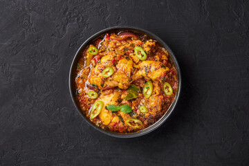 A Chicken Patiala in black bowl on dark slate table top. Murg Patiala is indian cuisine curry dish with chicken meat, spices, curd and cashew nut paste. Asian food and meal. Top view