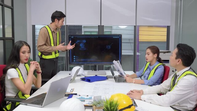 young Asian engineer is presenting the operation of the machine at a meeting. The atmosphere is controversial and stressful.
