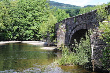 Fototapeta na wymiar An ancient bridge over the Mawddach River at Llanelltyd, Gwynedd, Wales, UK.