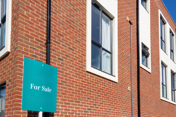 A for sale sign outside a block of modern flats or apartment block