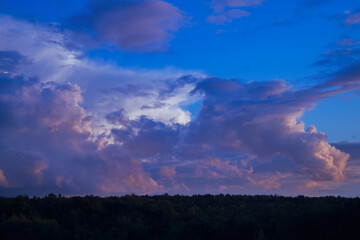 Fototapeta premium There are dramatic clouds in the dark sky as the sun sets. The sky is dominated by fuchsia, pink.