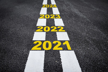 Number of 2021 to 2024 on asphalt road surface with marking lines, happy new year concept