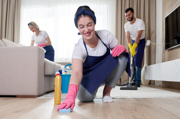 Professional cleaning service team cleans living room in modern apartment
