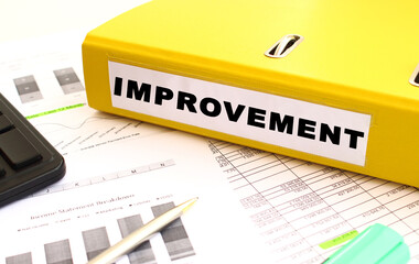 The yellow document folder is on the office desk. Nearby a calculator, finance graphs.