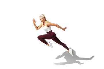 Fototapeta na wymiar Running. Beautiful young female athlete practicing on white studio background, portrait with shadow. Sportive fit model in motion and action. Body building, healthy lifestyle, style concept.