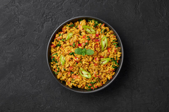Masala Egg Bhurji or Muttai Podimas in black bowl on dark slate table top. Anda Bhurji is indian cuisine scrambled eggs dish with spices. Asian food and meal. Top view