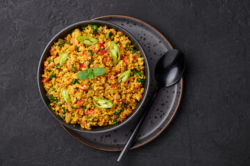 Masala Egg Bhurji or Muttai Podimas in black bowl on dark slate table top. Anda Bhurji is indian cuisine scrambled eggs dish with spices. Asian food and meal. Top view