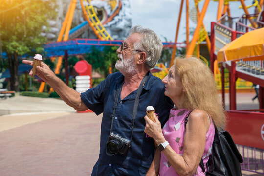 Grandpa and grandma visit an amusement park and happily eat ice cream.