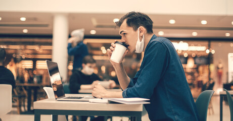 side view. casual young man with coffee takeaway sitting at a cafe table