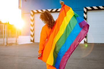 Young woman with LGBT rainbow flag  and protective  mask during preventing the spread of the epidemic and treating coronavirus and pandemic COVID-19.