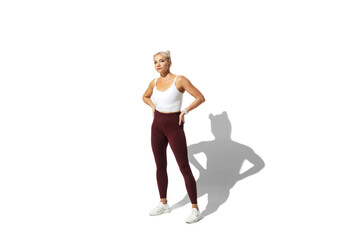 Obraz premium Posing. Beautiful young female athlete practicing on white studio background, portrait with shadow. Sportive fit model in motion, action. Body building, healthy lifestyle, style concept.