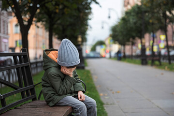 sad little boy sitting on a bench