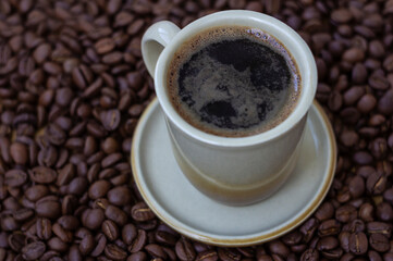 Obraz na płótnie Canvas Black coffee in light brown cup on coffee beans background
