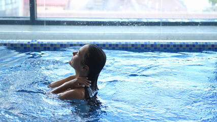 Close up of young woman is enjoying and having relax in swimming pool in a luxury wellness center.