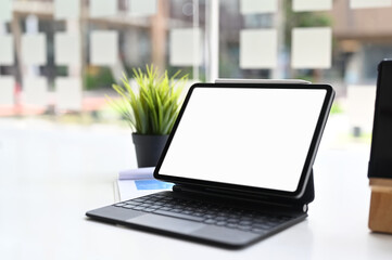 Cropped shot of tablet with smart keyboard on white table.Blank screen for graphics display montage.