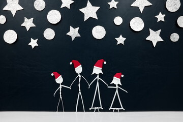 Family stick figure wearing santa hat in black background with stars and silver christmas ornaments. Celebrating holiday season together concept.