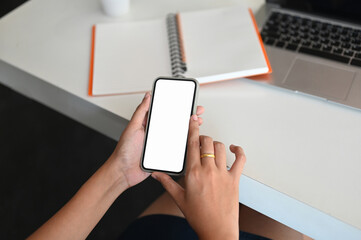 Top view businesswoman hands holding and using smartphone in modern office.