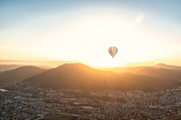 Cityscape with Mountains and Hot Air Balloon and Sunshine