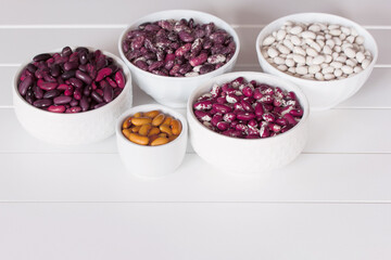 different types of red beans, white beans and yellow beans in white bowls on a white background close-up. background with different types of beans.