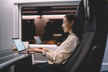 Smiling asian female passenger of train typing on laptop computer working on business trip,woman...
