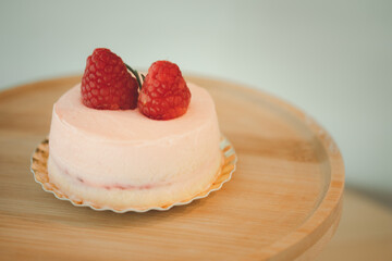 Pink mousse cake covered with pink cream rose on top with berry