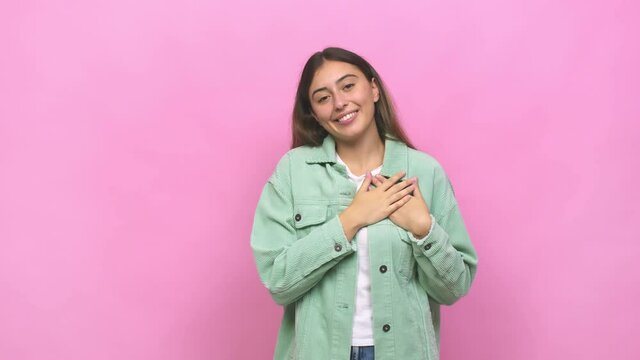 Young caucasian woman has friendly expression, pressing palm to chest love concept