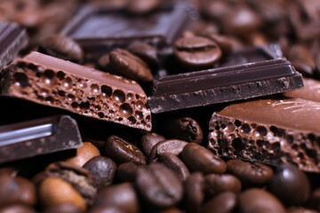 Close-up of dark roasted coffee beans and chocolate background. Aromatic coffee grains and sweet choco pieces macro photography