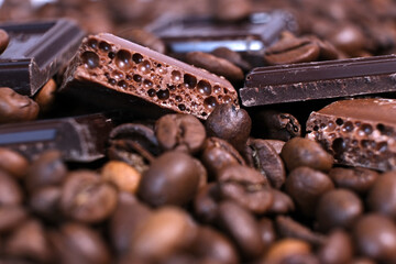 Close-up of dark roasted coffee beans and chocolate background. Aromatic coffee grains and sweet choco pieces macro photography,