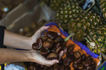 unrecognizable woman holding chestnuts in a greengrocer